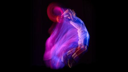 Basketball athlete making dunk with glowing neon motion trail on black backgroundの写真素材