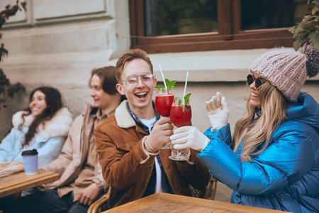Friends toasting with winter cocktails outdoors in cozy city cafe