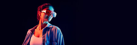 Stylish woman with red visor glasses posing under neon light expressing confidence. Bannerの写真素材