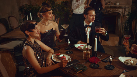 Smiling retro women and men enjoying elegant dinner party in vintage restaurantの写真素材