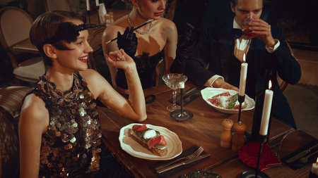 Happy retro friends standing at bar counter with cocktails in warm vintage lightingの写真素材