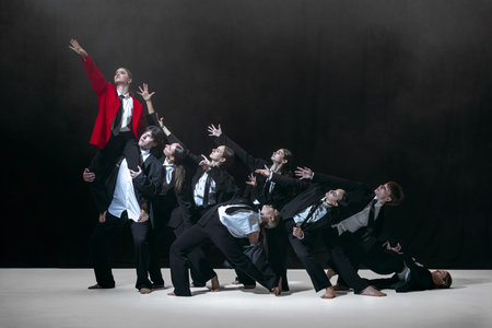 Collective reaching toward lifted individual in red jacket expressing strong emotional and social...