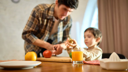Glass of orange juice on wooden table with bright cozy mood and soft family interactionの写真素材