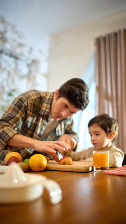 Orange juice glass in bright kitchen scene with lively warm family momentの写真素材