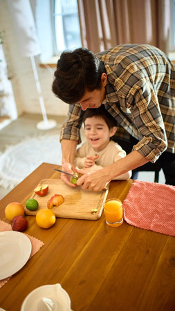Fresh orange juice in glass with warm smiling family moment and bright kitchen lightの写真素材