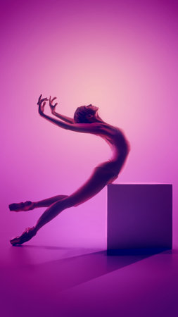 Ballerina arching backward on cube in vivid pink studio glowの写真素材