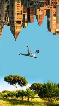 Bright poster of man falling between upside down skyscrapers and sunny green meadow.の写真素材
