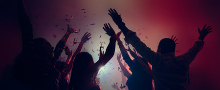 Crowd celebrating with raised hands and falling confetti.の写真素材