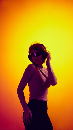 Woman in futuristic glasses and headphones posing in digital light.の写真素材