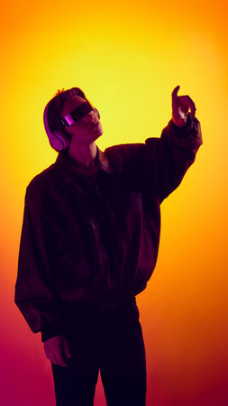 Man wearing futuristic glasses and headphones reaching forward in neon light.の写真素材