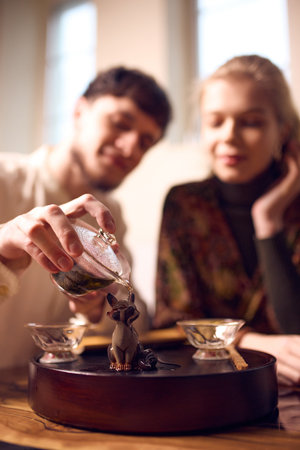 Man pouring tea while woman watches with calm expression.
