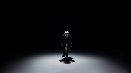 Cyclist riding in spotlight on dark background with copy space.の写真素材