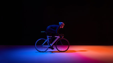 Professional cyclist riding road bike under neon lighting with copy spaceの写真素材