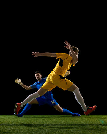 Soccer striker volley shot challenged by goalkeeper on dark background.の写真素材