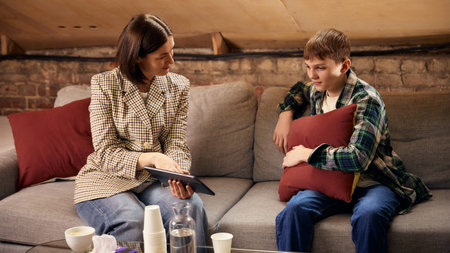 Teenage boy in psychology session with female therapist using digital tablet.の写真素材