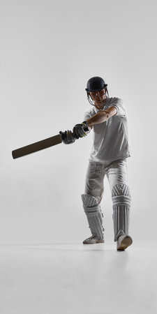 Cricket player swinging bat in powerful drive isolated on white background