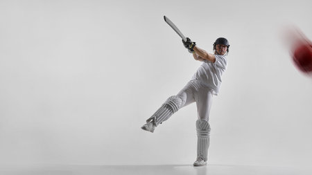 Cricket batsman striking ball in dynamic follow through isolated on white background.