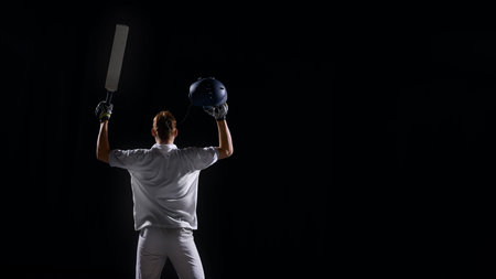 Rear view cricket player lifting bat and helmet in triumphant pose.の写真素材