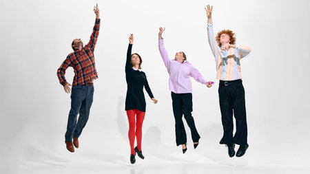 Four models reaching upward in coordinated studio fashion look on white background.