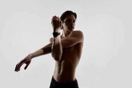 Athletic man stretching with smartwatch in modern studio.