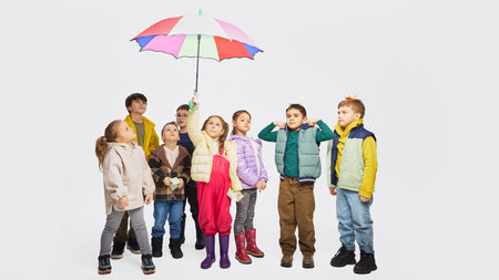 Group of children looking up under colorful umbrella wearing mid season kids fashion clothing.の写真素材