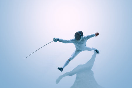 Male fencer attacking with epee viewed from above in studio.