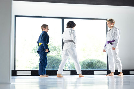 Children line up for judo drill as female coach evaluates their technique