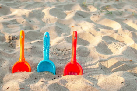 a red, orange and blue baby spatula on the beach on sunset in summer conceptの写真素材