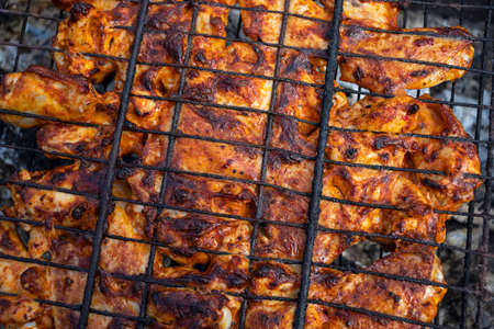 Tasty chicken legs and wings on the grill with fire flames.の写真素材