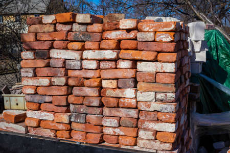 A pile of building materials, stack of new red bricks for construction are accurately put together