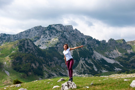 two long hair girls happy jump in mountains with exciting view of Montenegro, Durmitor, back viewの写真素材