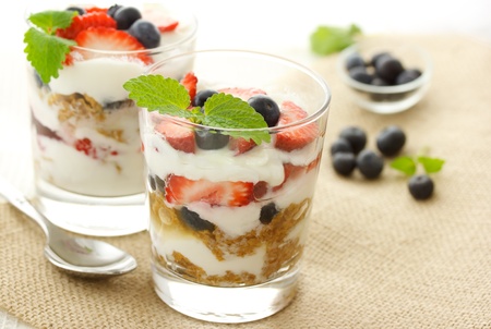 Vanilla yogurt over strawberries, blueberries and lemon balmの写真素材