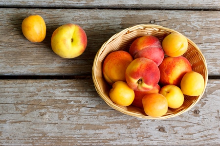 Juicy peaches and apricots in basketの写真素材
