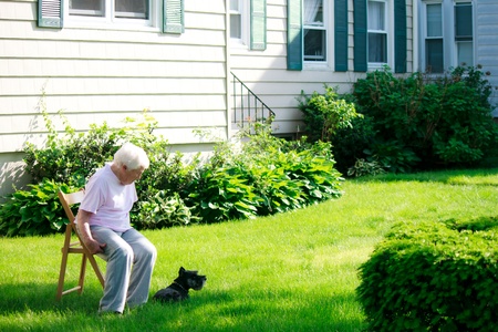 Senior lady with her dog relaxing in front yardの写真素材