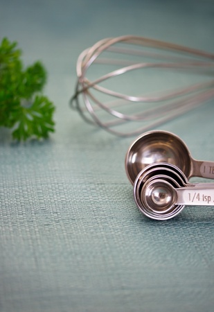 Measuring spoons with wire whisk and parsley