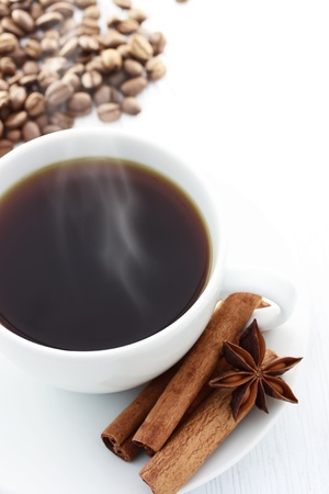 Cup of Hot Coffee with Cinnamon Sticks, Star Anise and Coffee Beans on a white tableの写真素材