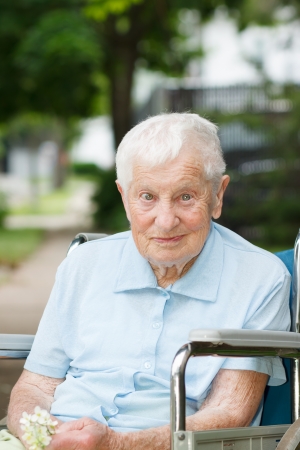 Happy senior lady in wheelchair smiling outsideの写真素材