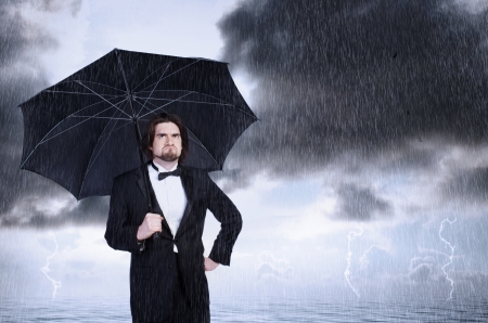 Unhappy Man Holding Umbrella in a Rain Storm and Frowningの写真素材