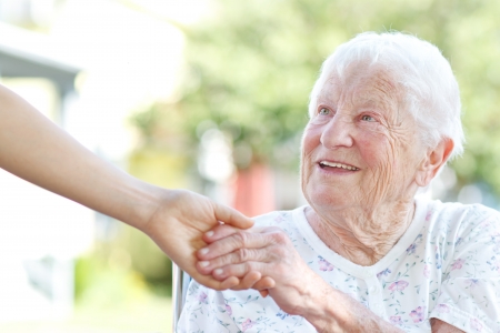 Happy senior woman holding hands with caretakerの写真素材