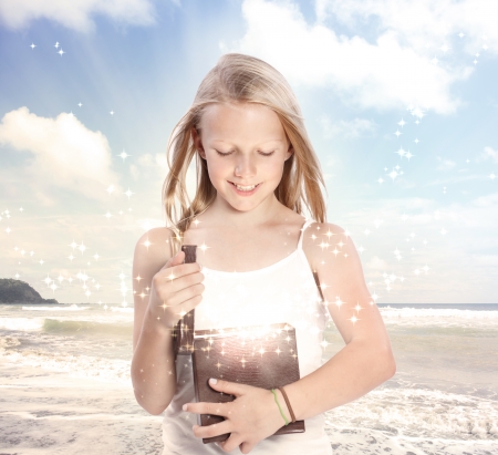 Happy Young Blonde Girl Opening a Gift Box on the Beachの写真素材
