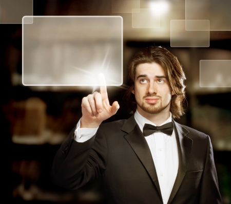 Man with Bow Tie  Looking and Pointing a Touch Screenの写真素材