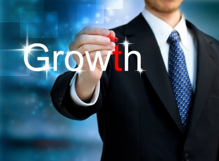 Young business man writing the word Growth with red penの写真素材