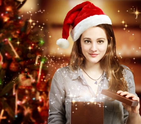Happy Girl with Santa Hat Opening a Gift Boxの写真素材