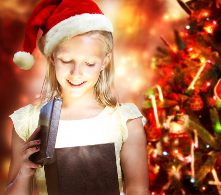 Happy Blonde Girl with Santa Hat Opening a Gift Boxの写真素材