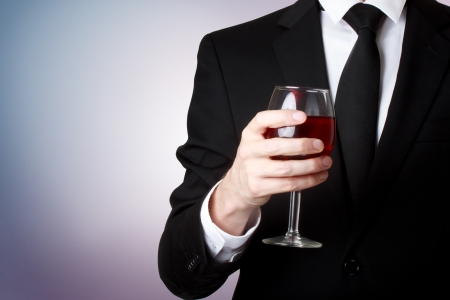 Elegant young man holding a glass of red wine の写真素材