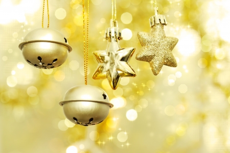 Christmas bells and stars hanging over golden bokeh backgroundの写真素材