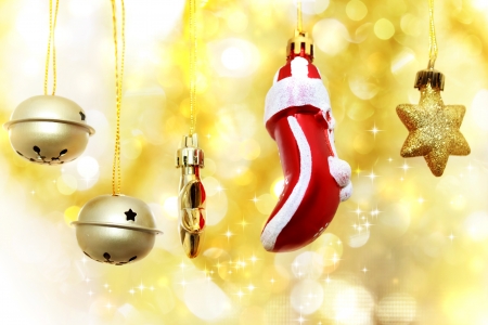 Christmas bells, glove and stars hanging over golden bokeh backgroundの写真素材