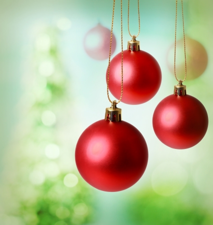 Christmas red ornaments over green tree lights backgroundの写真素材