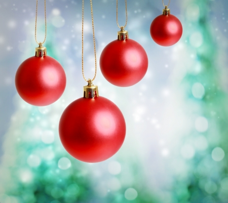Red Christmas ornaments with green-blue Christmas tree lights backgroundの写真素材