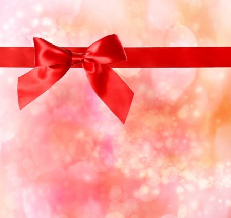 Red bow and ribbon with red - orange bokeh lights background の写真素材